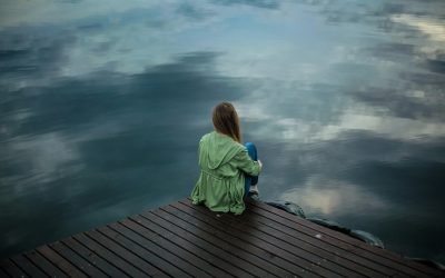 a woman sitting on a dock looking at the water